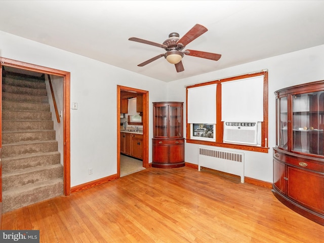 unfurnished living room featuring radiator, sink, ceiling fan, cooling unit, and light hardwood / wood-style floors