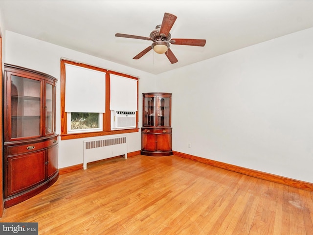 unfurnished room featuring ceiling fan, radiator heating unit, light hardwood / wood-style floors, and cooling unit