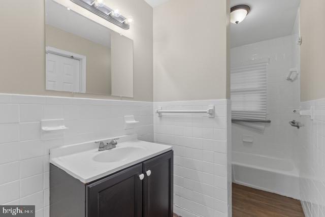 bathroom with vanity, hardwood / wood-style floors, and tile walls