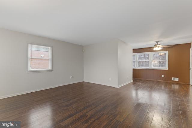 unfurnished room with plenty of natural light, dark hardwood / wood-style floors, and ceiling fan