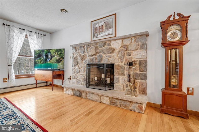 living room featuring a baseboard radiator, wood-type flooring, a fireplace, and a textured ceiling