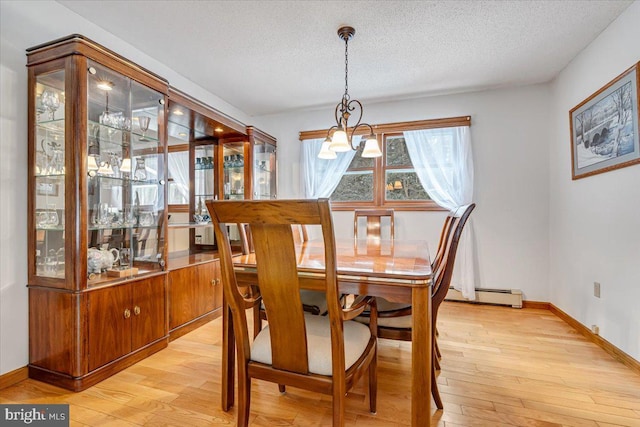 dining space featuring a baseboard heating unit, light hardwood / wood-style floors, a chandelier, and a textured ceiling