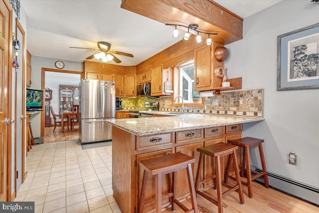 kitchen with decorative backsplash, a breakfast bar area, kitchen peninsula, and appliances with stainless steel finishes