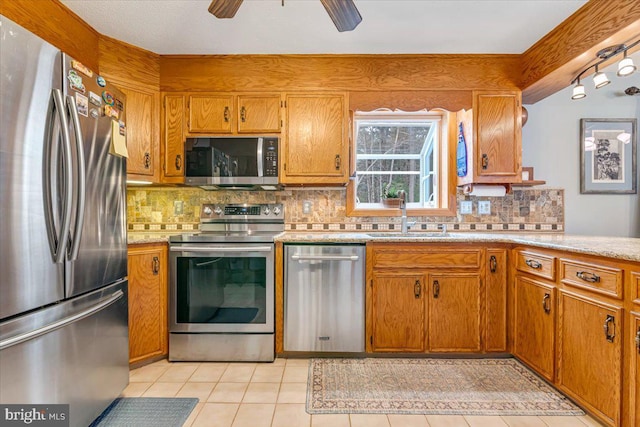 kitchen with sink, light tile patterned floors, ceiling fan, appliances with stainless steel finishes, and decorative backsplash