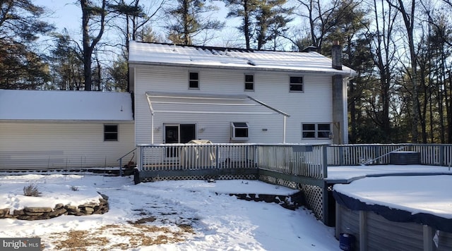 snow covered rear of property with a wooden deck