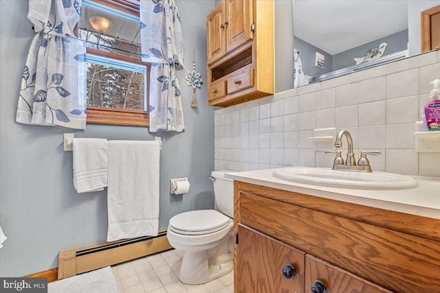 bathroom with tile walls, vanity, a baseboard heating unit, toilet, and tile patterned floors