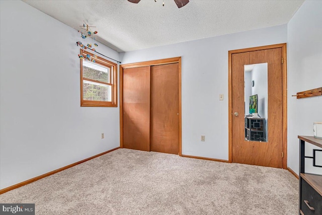 unfurnished bedroom featuring ceiling fan, carpet floors, a closet, and a textured ceiling