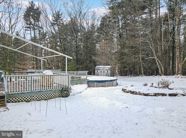 yard covered in snow featuring a deck and a shed