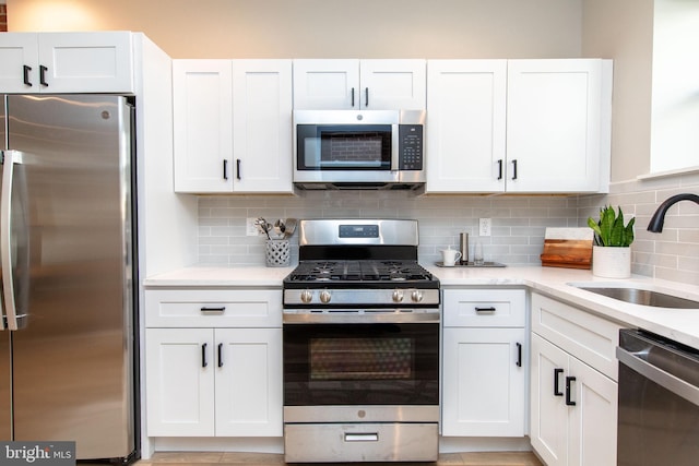 kitchen featuring stainless steel appliances, white cabinetry, sink, and backsplash