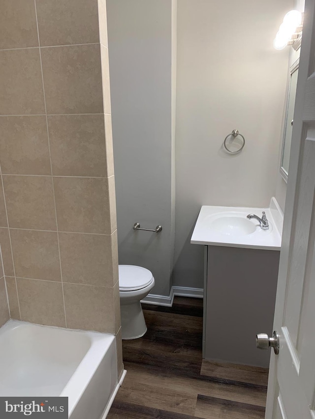 bathroom with hardwood / wood-style flooring, vanity, a washtub, and toilet