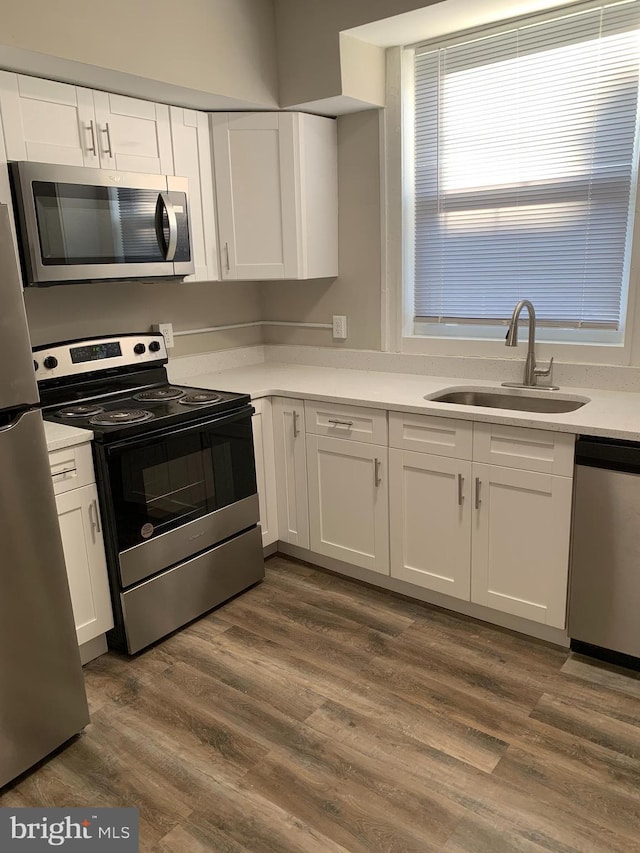 kitchen with white cabinetry, appliances with stainless steel finishes, dark hardwood / wood-style floors, and sink