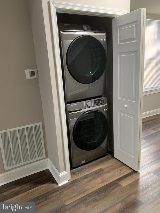 clothes washing area with stacked washer / dryer and wood-type flooring