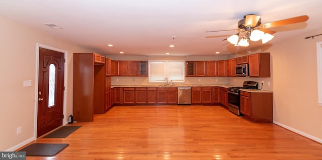 kitchen with ceiling fan, appliances with stainless steel finishes, sink, and light wood-type flooring