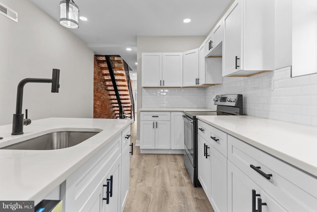 kitchen featuring sink, white cabinetry, electric stove, light stone countertops, and light hardwood / wood-style floors