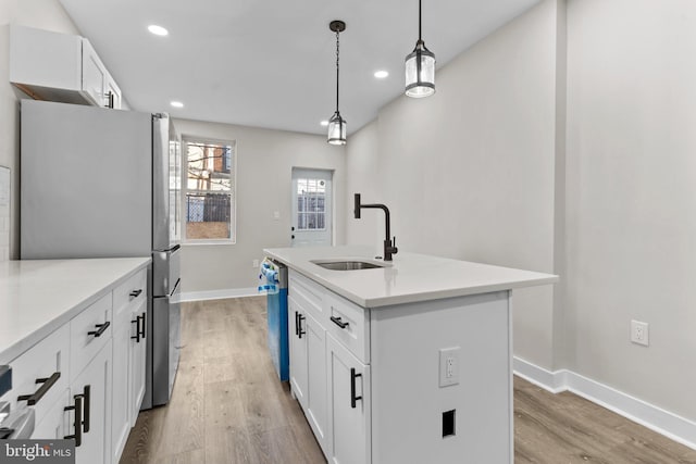 kitchen with sink, appliances with stainless steel finishes, an island with sink, pendant lighting, and white cabinets