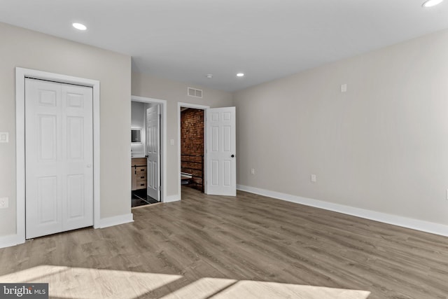 unfurnished bedroom with connected bathroom and light hardwood / wood-style flooring