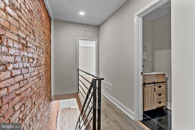 hall with hardwood / wood-style flooring and brick wall