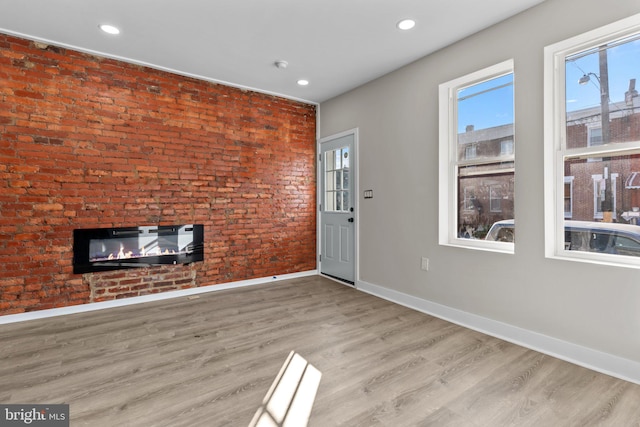 entryway with plenty of natural light, brick wall, and light wood-type flooring