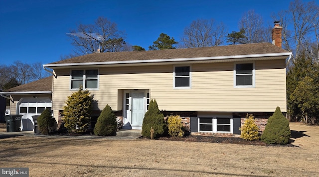 split foyer home featuring a garage and a front yard