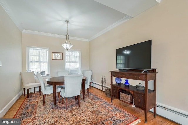 dining room featuring a baseboard heating unit, ornamental molding, wood finished floors, and baseboards