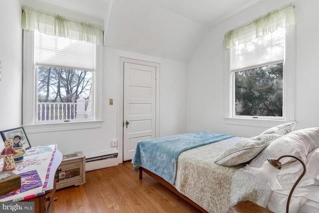 bedroom with a baseboard heating unit, lofted ceiling, and wood finished floors