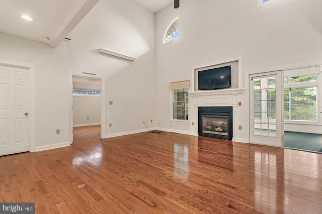 unfurnished living room featuring hardwood / wood-style flooring, plenty of natural light, and a high ceiling