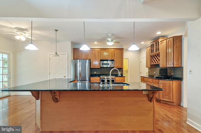 kitchen featuring a spacious island, stainless steel appliances, sink, and light wood-type flooring