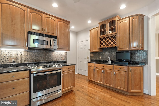 kitchen featuring light hardwood / wood-style flooring, stainless steel appliances, and dark stone counters