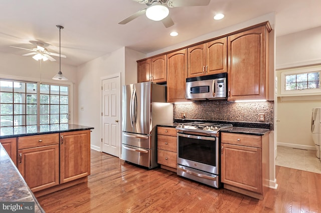 kitchen with hanging light fixtures, ceiling fan, stainless steel appliances, hardwood / wood-style floors, and decorative backsplash