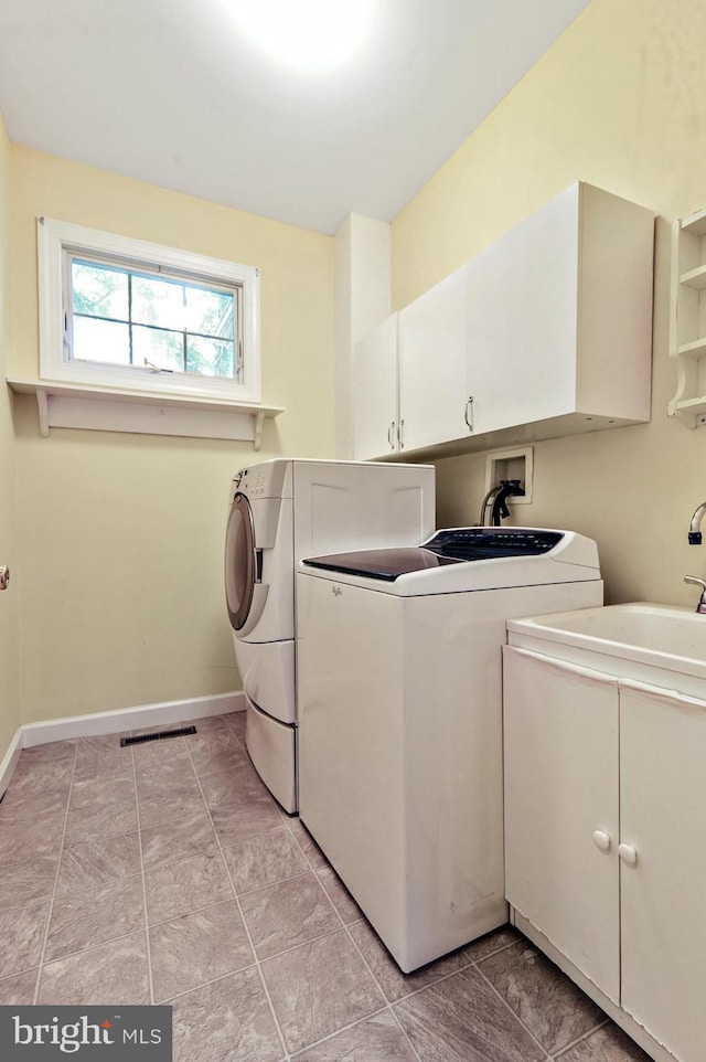 washroom with cabinets, washer and dryer, and light tile patterned floors