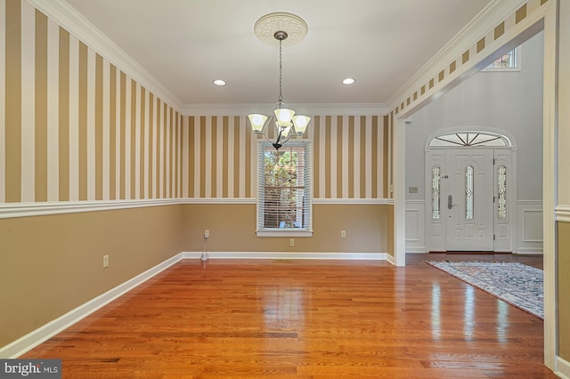 unfurnished dining area featuring ornamental molding, hardwood / wood-style floors, and a notable chandelier