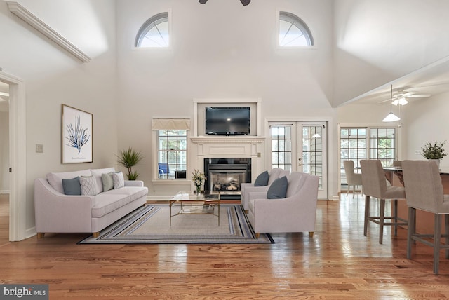 living room featuring light wood-type flooring, ceiling fan, and french doors