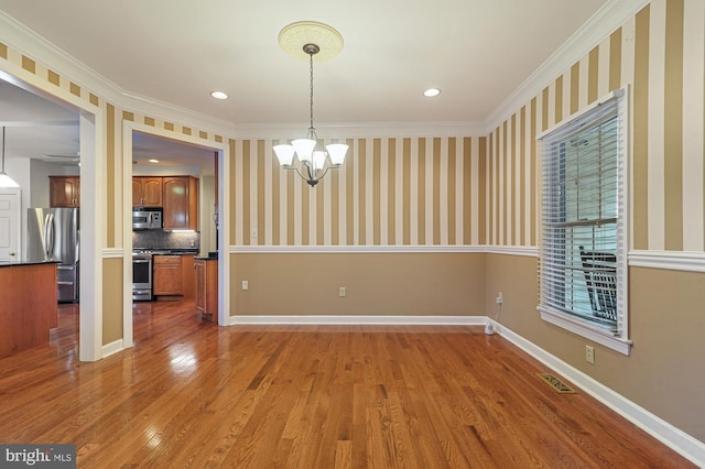 unfurnished dining area with a notable chandelier, dark wood-type flooring, and ornamental molding