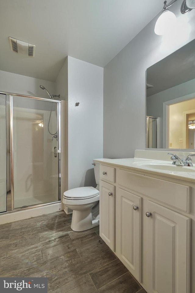 bathroom featuring hardwood / wood-style flooring, vanity, toilet, and an enclosed shower