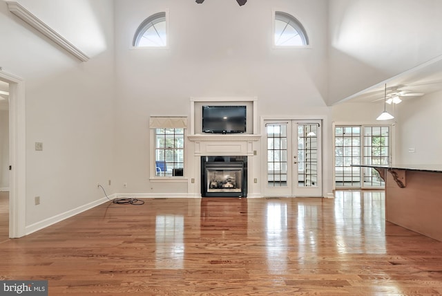 unfurnished living room featuring a towering ceiling, ceiling fan, and light hardwood / wood-style flooring