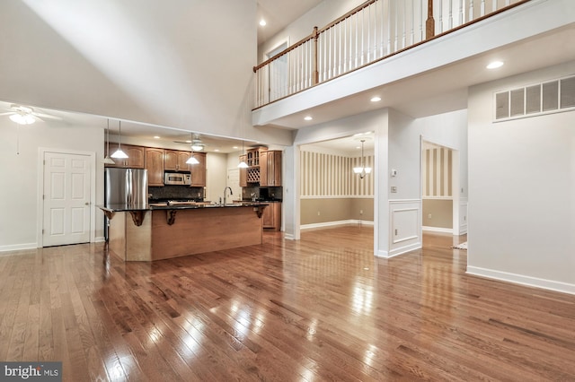 unfurnished living room featuring ceiling fan, hardwood / wood-style floors, and a high ceiling