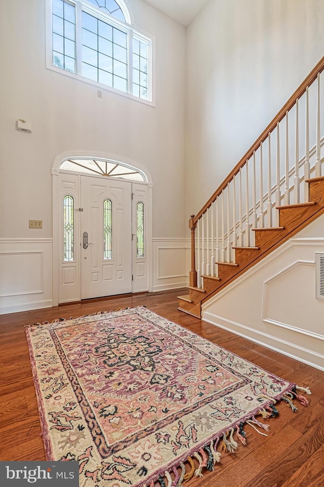 foyer entrance with hardwood / wood-style flooring and a towering ceiling