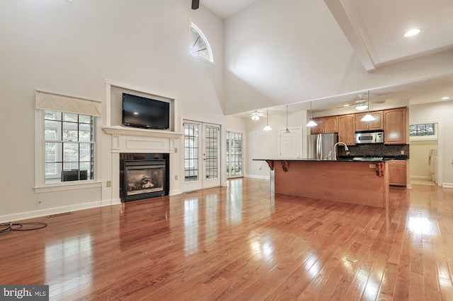 unfurnished living room with ceiling fan, a healthy amount of sunlight, and light wood-type flooring