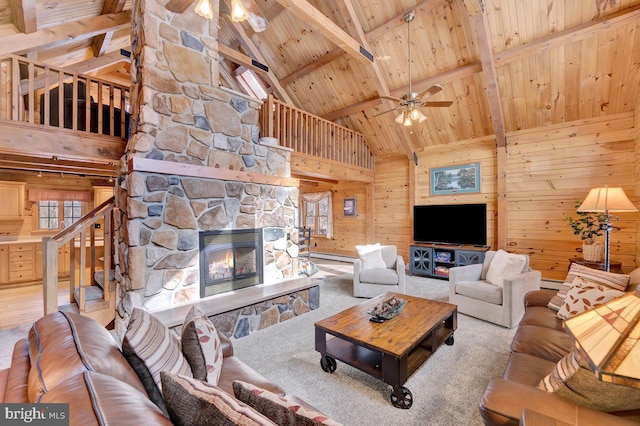 living room with a stone fireplace, wood walls, ceiling fan, wood ceiling, and beam ceiling