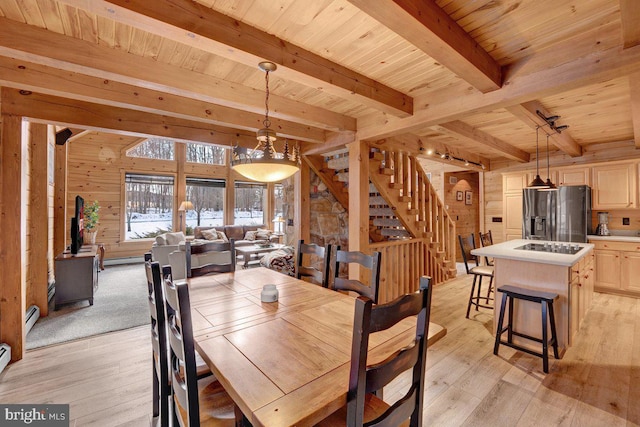 dining room with beam ceiling, wooden walls, wood ceiling, and light hardwood / wood-style flooring