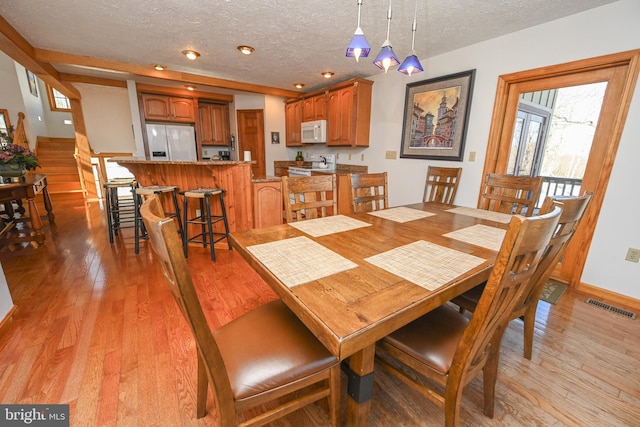 dining area featuring a textured ceiling and light hardwood / wood-style floors