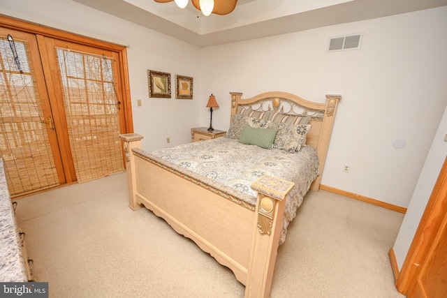 carpeted bedroom featuring ceiling fan, a tray ceiling, and access to exterior