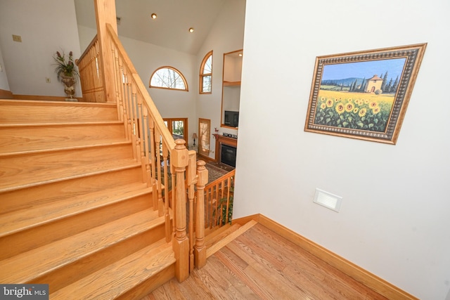 staircase featuring hardwood / wood-style flooring and high vaulted ceiling