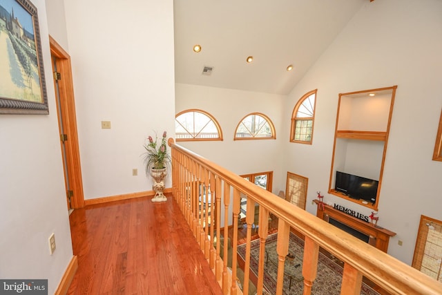 hallway with wood-type flooring and high vaulted ceiling