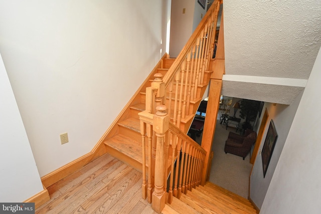 stairway with hardwood / wood-style floors and a textured ceiling