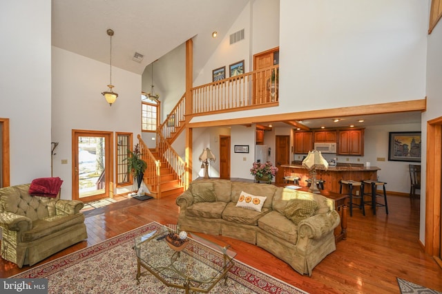 living room with a towering ceiling and light wood-type flooring