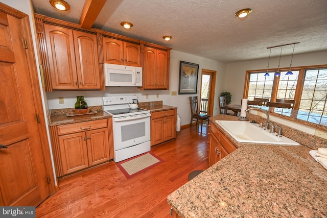 kitchen with sink, white appliances, light hardwood / wood-style flooring, a textured ceiling, and decorative light fixtures