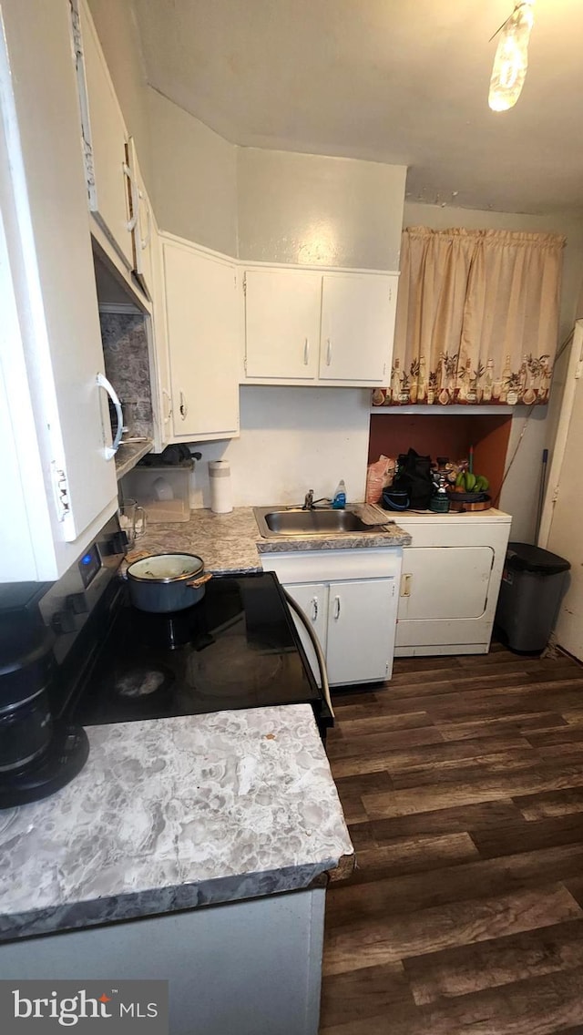 kitchen with sink, dark wood-type flooring, range with electric cooktop, white cabinets, and washer / clothes dryer