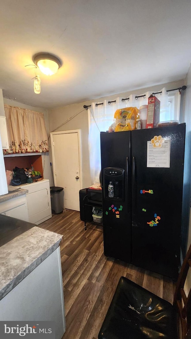 kitchen featuring light brown cabinetry, dark wood-type flooring, washing machine and dryer, and black fridge