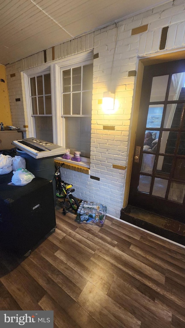 interior space with brick wall and dark hardwood / wood-style floors